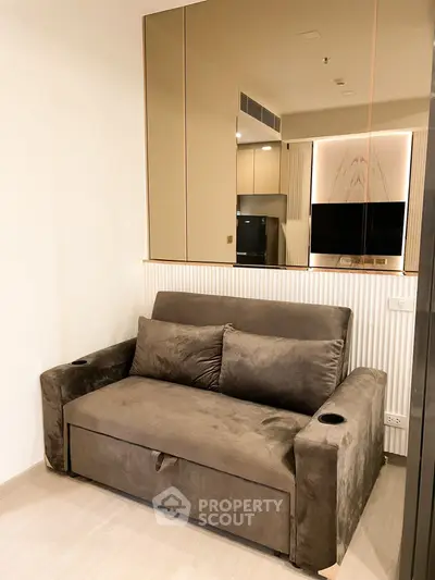 Modern living room with plush sofa and mirrored wall for spacious feel