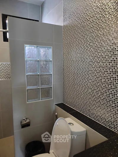 Modern bathroom with stylish mosaic tiles and glass block partition.