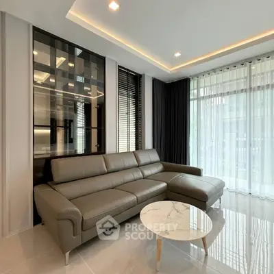 Modern living room with sleek leather sofa and marble coffee table, featuring floor-to-ceiling windows and elegant decor.