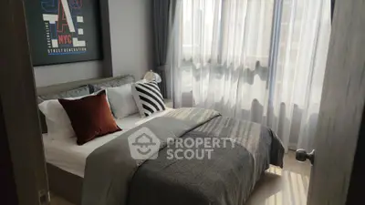 Cozy bedroom with modern decor and ample natural light through large windows.