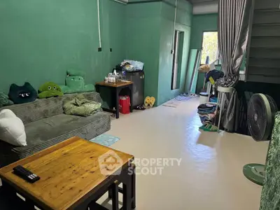 Cozy living room with green walls, comfortable sofa, and wooden table, perfect for relaxation.