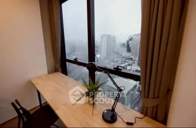 Modern study room with city view, featuring a sleek desk and lamp.