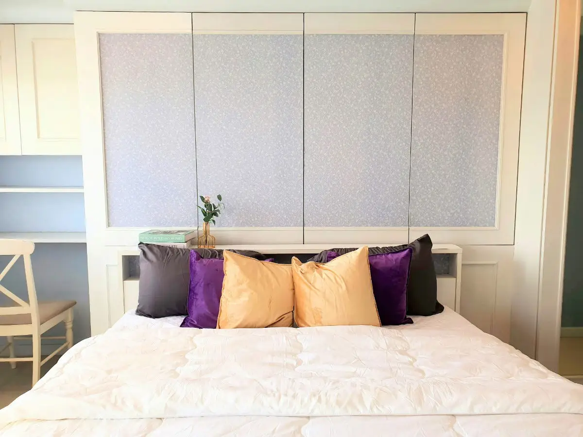 Cozy bedroom with stylish pillows and elegant decor, perfect for relaxation and comfort.