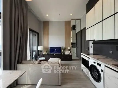 Modern living room with open kitchen, featuring sleek appliances and stylish decor.