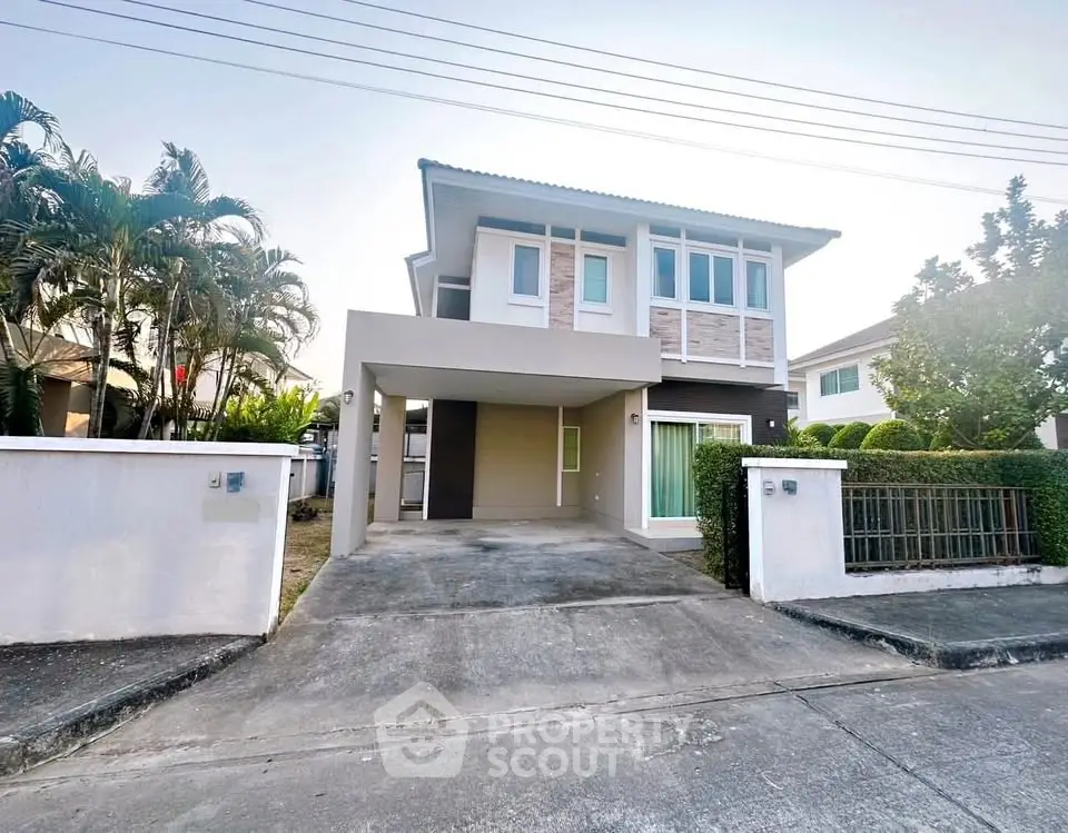 Modern two-story house with driveway and landscaped garden in suburban neighborhood.