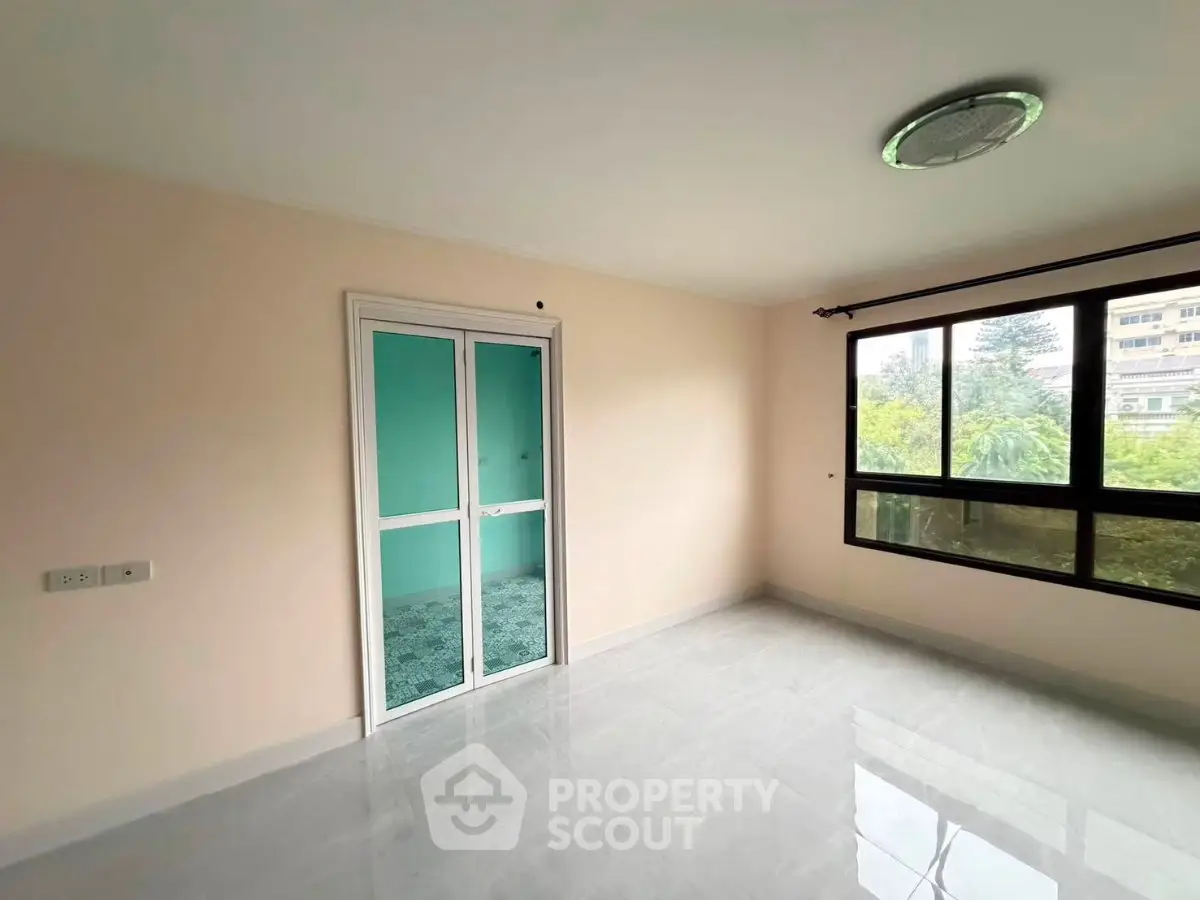 Spacious empty room with large window and sliding glass door, offering ample natural light and serene views.