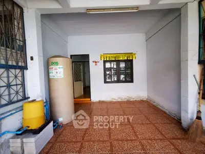 Spacious tiled area with water tank, ideal for storage or utility use.