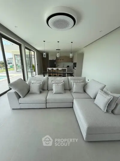 Spacious modern living room with elegant gray sectional sofa and open kitchen layout, perfect for entertaining.