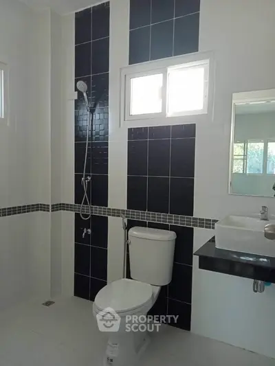 Modern bathroom with sleek black and white tile design and contemporary fixtures.