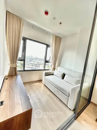 Bright and cozy living room with large window and modern sofa, offering stunning city views.
