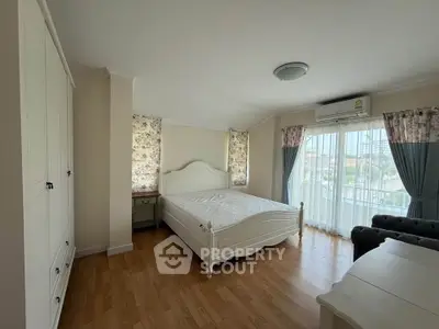 Spacious bedroom with elegant decor and large windows offering natural light.