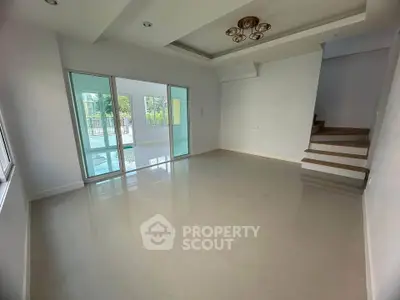Spacious modern living room with large windows and elegant staircase