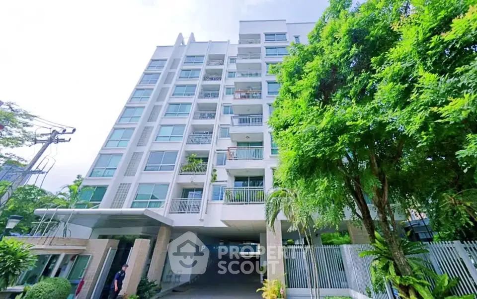 Modern apartment building with lush greenery and secure entrance in urban setting.
