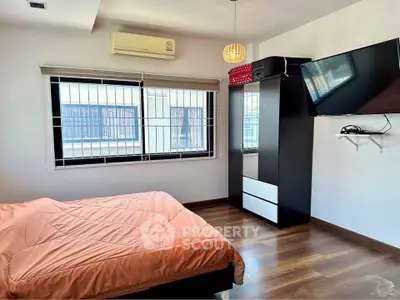 Modern bedroom with sleek design, featuring a wall-mounted TV and large window for natural light.