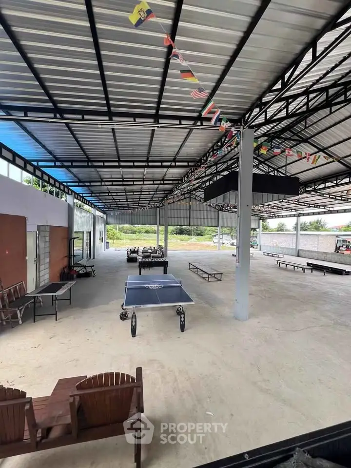 Spacious covered outdoor area with table tennis and seating, ideal for recreation and events.