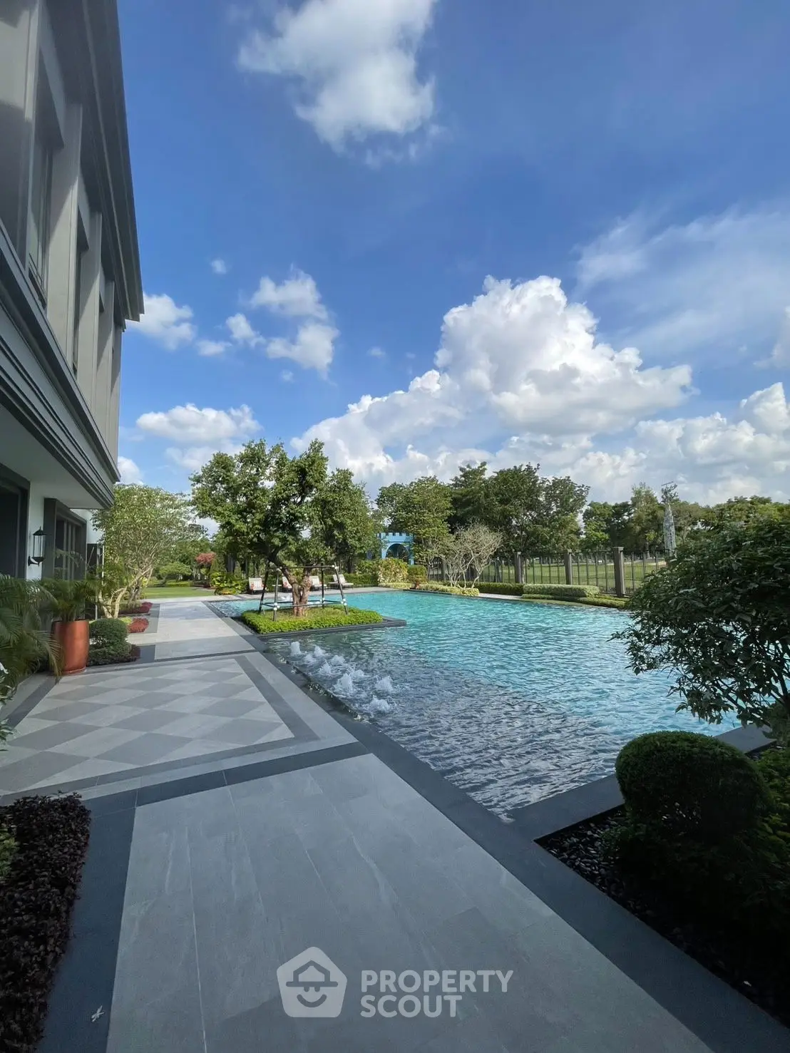 Luxurious outdoor pool area with lush greenery and clear blue skies