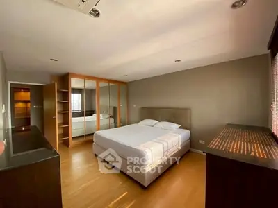 Spacious bedroom with large mirrored wardrobe and natural light