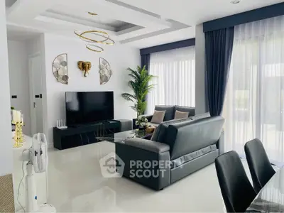 Luxurious modern living room with sleek black sofa, large TV, and elegant decor in a bright, airy space.