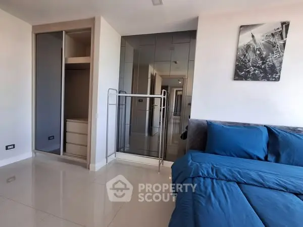Modern bedroom with blue bedding and built-in wardrobe, featuring sleek design and ample storage space.