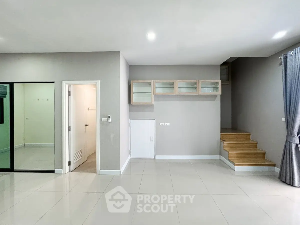 Spacious modern living area with sleek staircase and glass cabinets