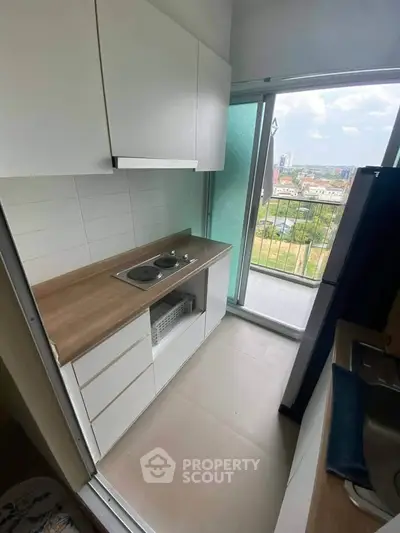 Modern kitchen with sleek cabinets and balcony view in urban apartment