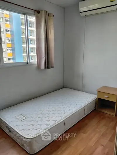 Cozy bedroom with single bed, window view, and air conditioning in modern apartment.