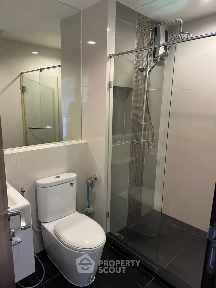 Modern bathroom with glass shower and sleek fixtures in contemporary apartment.