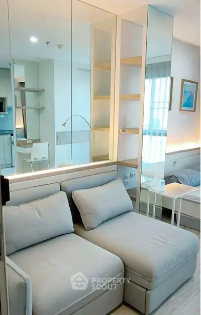 Modern living room with stylish decor and mirrored wall in a cozy apartment.
