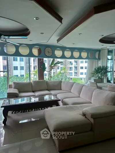 Spacious living room with large sectional sofa and modern decor, offering a bright and inviting atmosphere.