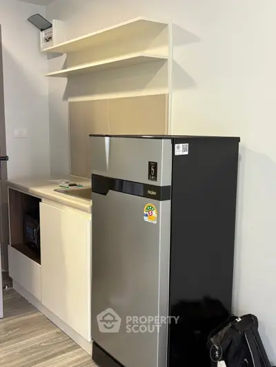 Modern kitchen with sleek fridge and storage cabinets in a stylish apartment.