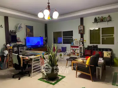 Cozy living room with modern decor, featuring a TV, comfortable seating, and indoor plants.