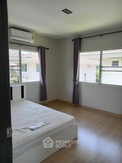 Bright and airy bedroom with large windows and modern air conditioning unit.