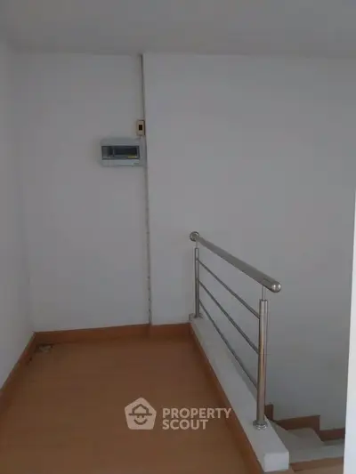 Minimalist stairway corner with metal railing and wooden flooring