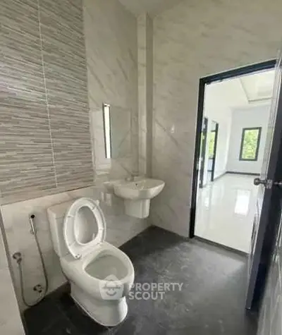 Modern bathroom with sleek design and open doorway to bright interior space.