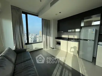 Modern living room with city view, featuring sleek furniture and a compact kitchen area.