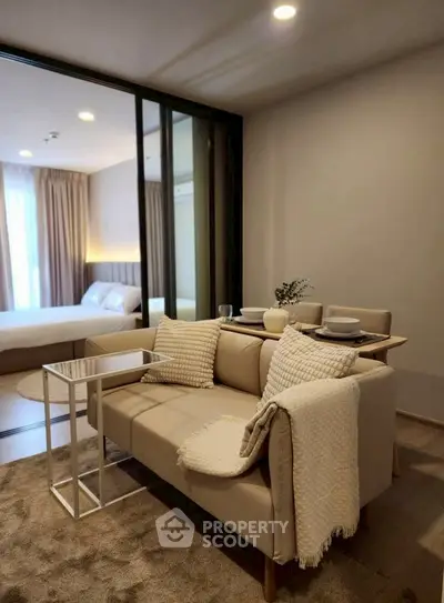 Modern living room with cozy beige sofa and elegant dining setup, adjacent to a stylish bedroom.
