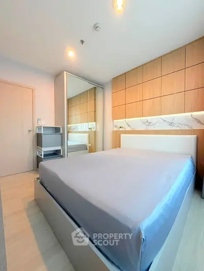 Modern bedroom with sleek design, featuring a large bed, mirrored wardrobe, and stylish wood paneling.