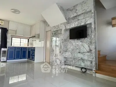 Modern living room with marble accent wall and sleek kitchen in open layout
