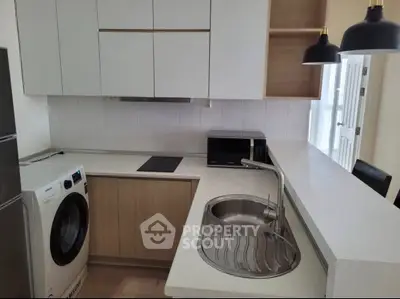 Modern kitchen with sleek design, featuring washing machine and microwave for convenient living.