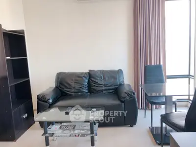 Modern living room with black leather sofa and glass coffee table in bright apartment.