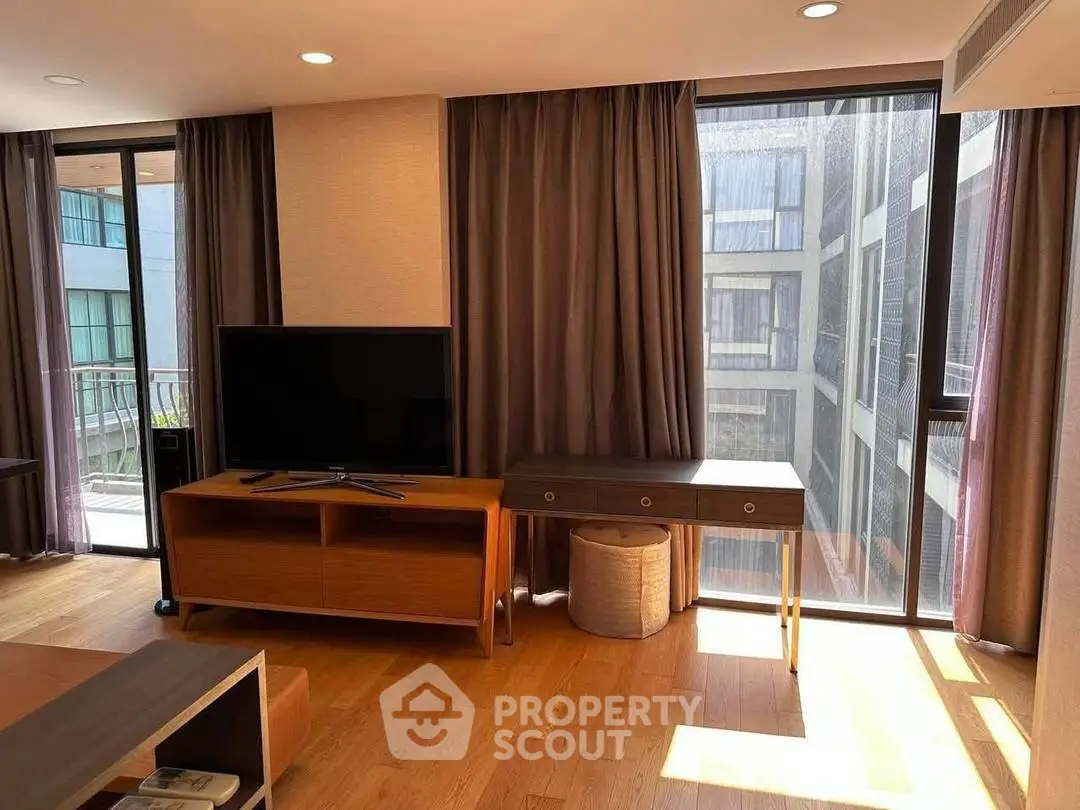 Modern living room with large windows and stylish furniture in urban apartment.