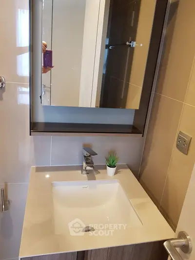 Modern bathroom with sleek sink and mirror cabinet, featuring elegant fixtures and neutral tones.