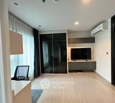 Modern living room with sleek furniture and large window, featuring a TV and air conditioning.