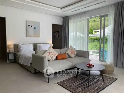 Modern living room with cozy sofa and large windows overlooking lush greenery.