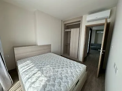 Modern bedroom with wooden flooring and built-in wardrobe, featuring a comfortable bed and air conditioning.