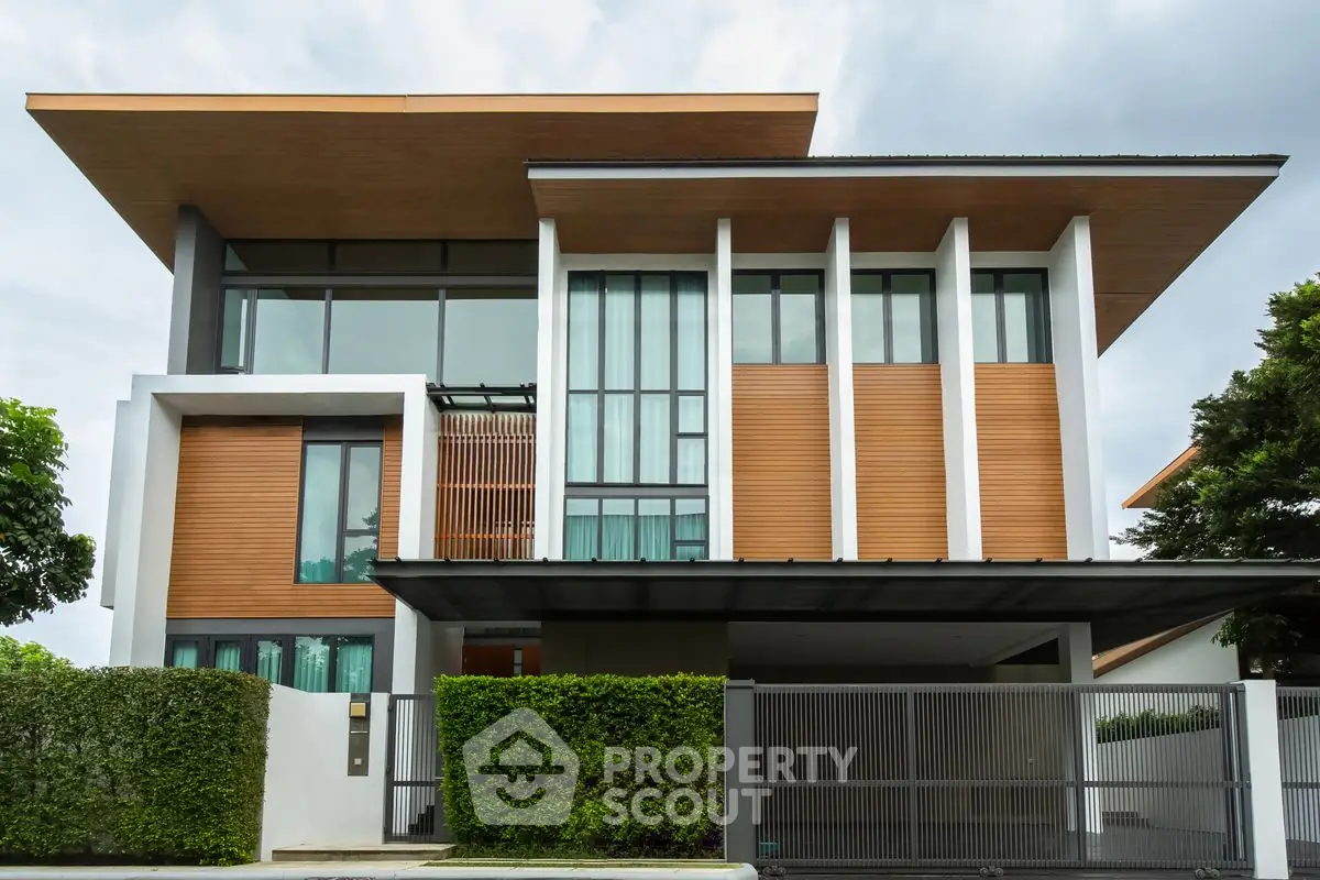 Modern architectural home with sleek design and large windows, surrounded by lush greenery.
