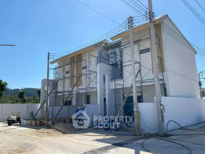 Modern townhouse under construction with scaffolding and clear blue sky.
