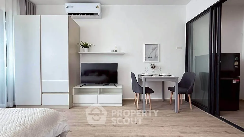 Modern studio apartment with sleek furniture and open layout, featuring a cozy dining area and stylish decor.