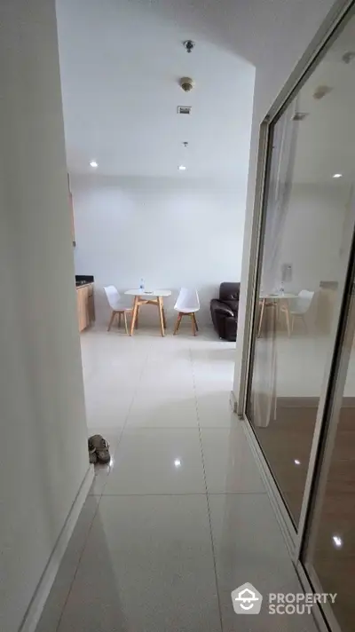 Modern apartment hallway leading to a cozy dining area with sleek furniture.