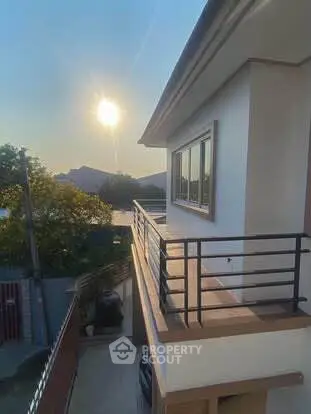 Stunning modern house exterior with balcony and sunset view.